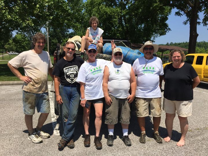 People standing together in front of a ple of trash.